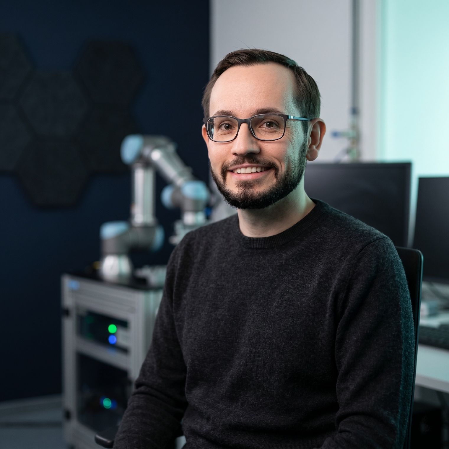 Maik Luxa im Forschungsumfeld am Fraunhofer EZRT, Roboterarm im Hintergrund